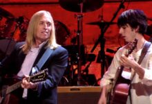 Tom Petty and Dhani Harrison playing acoustic guitars on the red-lit Concert for George stage
