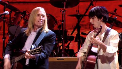 Tom Petty and Dhani Harrison playing acoustic guitars on the red-lit Concert for George stage