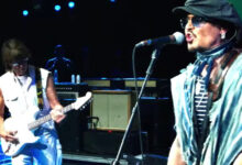 Johnny Depp singing beside Jeff Beck playing a white guitar on stage