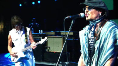 Johnny Depp singing beside Jeff Beck playing a white guitar on stage