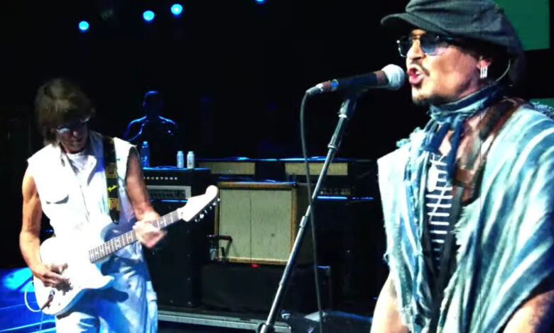 Johnny Depp singing beside Jeff Beck playing a white guitar on stage