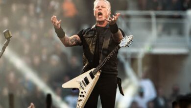 James Hetfield onstage with raised hands and a white guitar