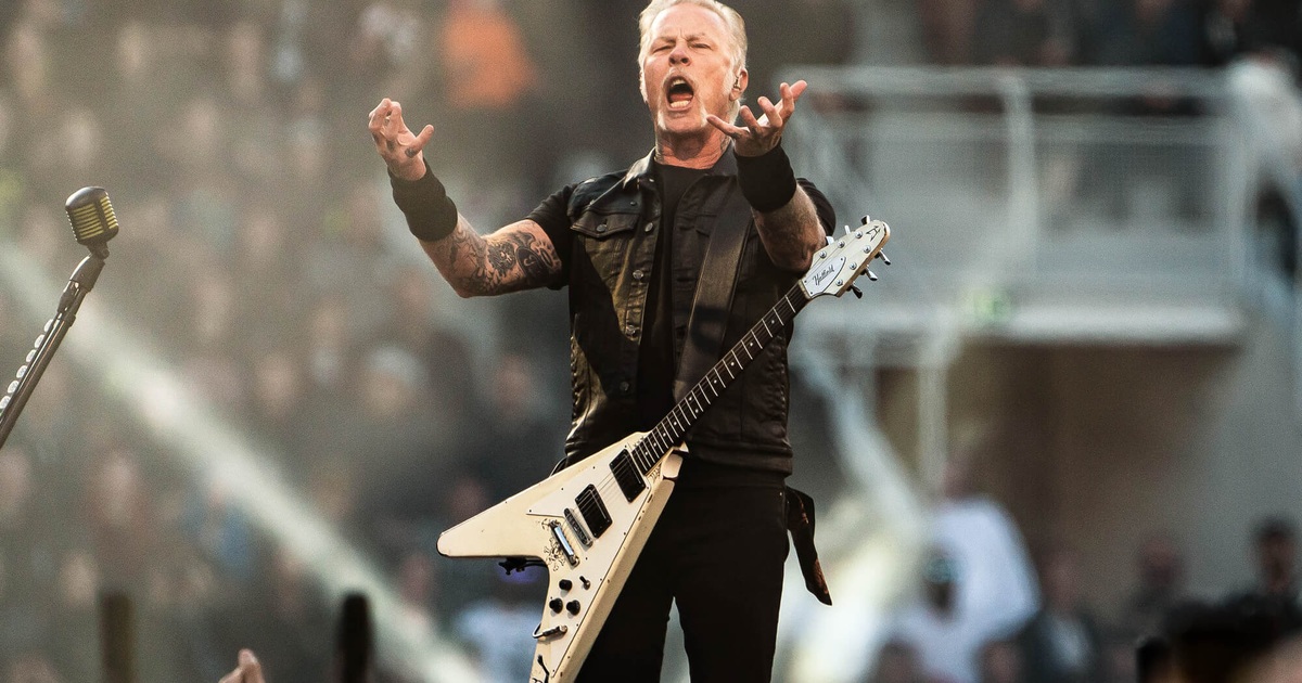 James Hetfield onstage with raised hands and a white guitar