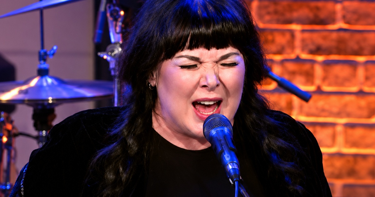 Ann Wilson singing into a microphone with blue and amber stage lighting
