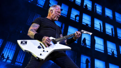 Edited image of James Hetfield playing a white guitar against blue barred-window visuals at Sphere