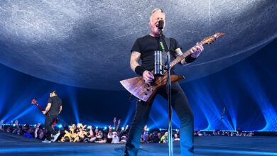 James Hetfield singing and playing guitar at Sphere beneath a curved gray backdrop and blue lights