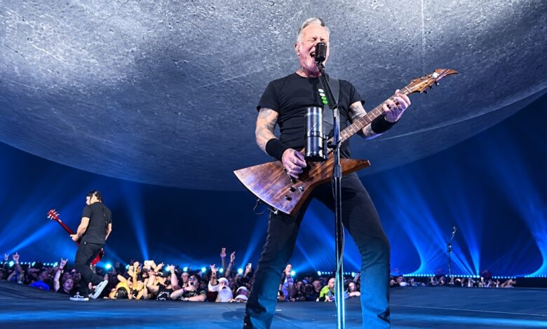 James Hetfield singing and playing guitar at Sphere beneath a curved gray backdrop and blue lights
