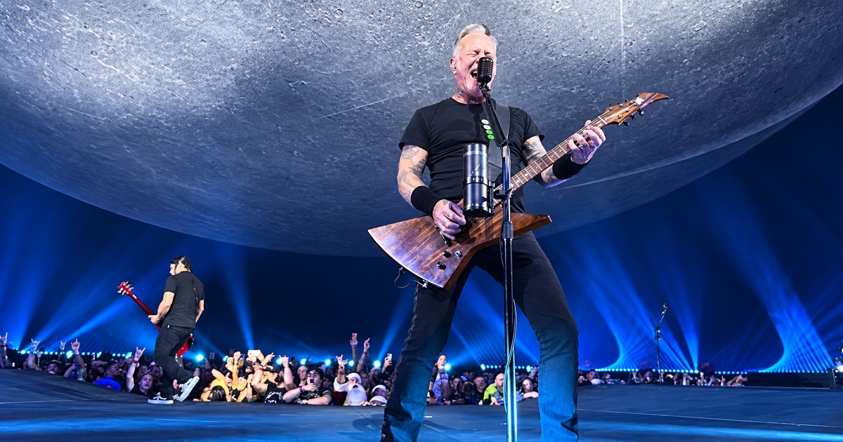 James Hetfield singing and playing guitar at Sphere beneath a curved gray backdrop and blue lights