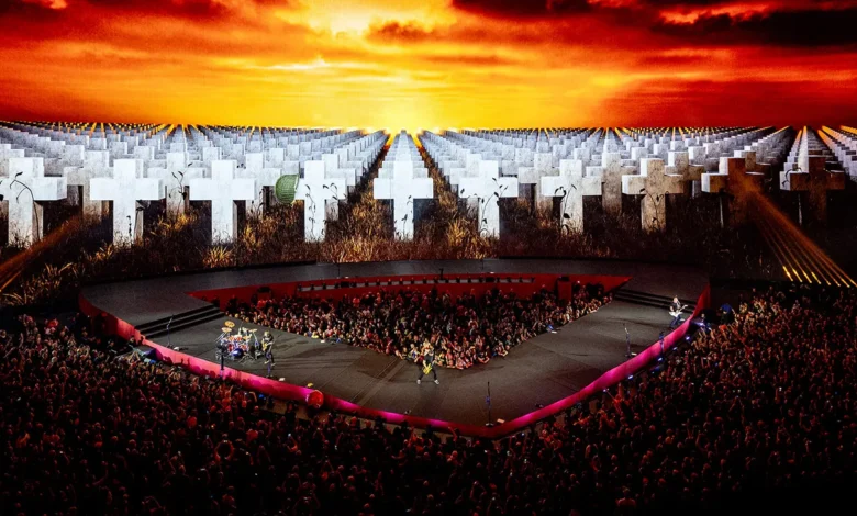 Metallica onstage at Sphere, with the audience beneath a screen showing white crosses and a fiery sky.