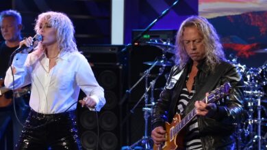 Miley Cyrus singing beside James Hetfield as he plays guitar.