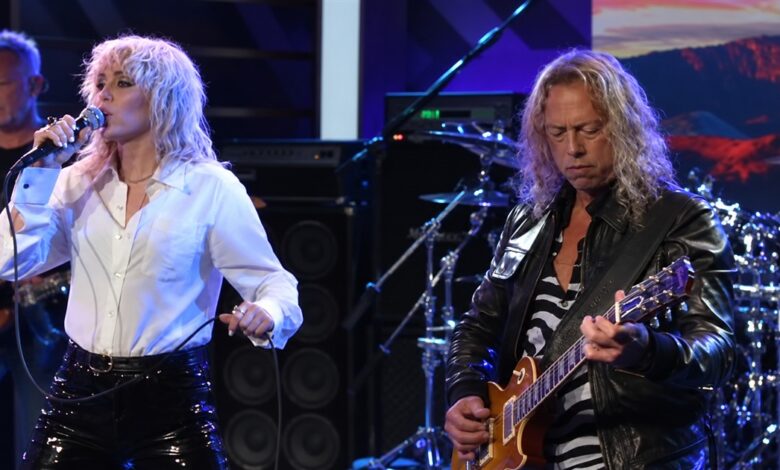 Miley Cyrus singing beside James Hetfield as he plays guitar.