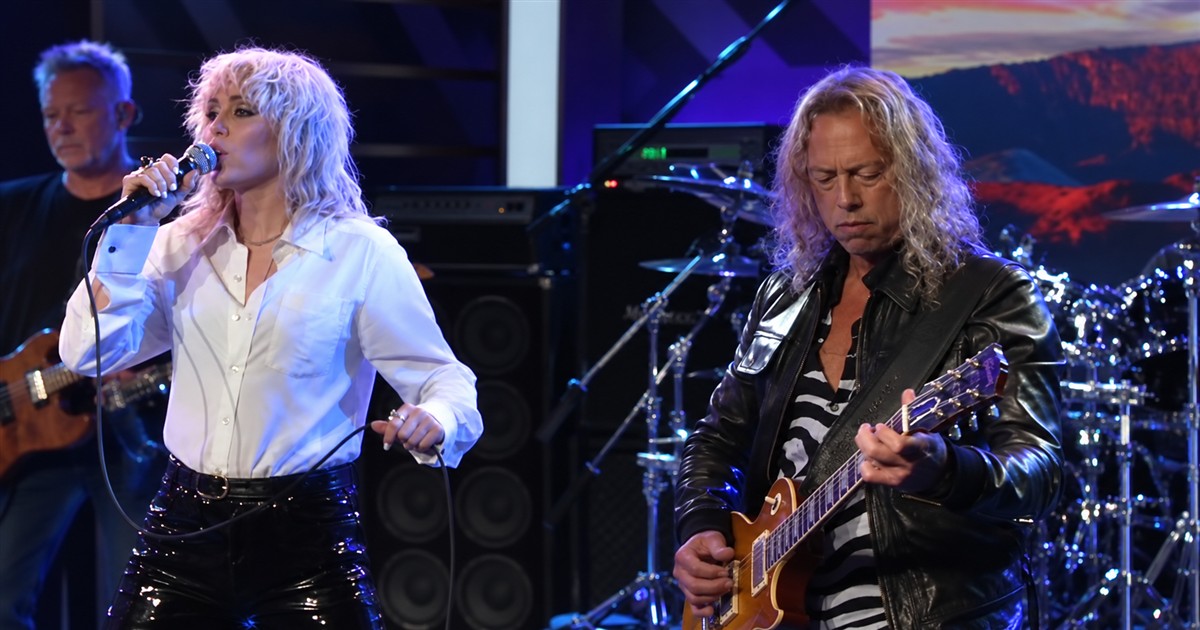 Miley Cyrus singing beside James Hetfield as he plays guitar.