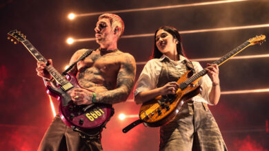 Edited concert photograph of NeNe Royal playing guitar beside an Avenged Sevenfold guitarist in Singapore
