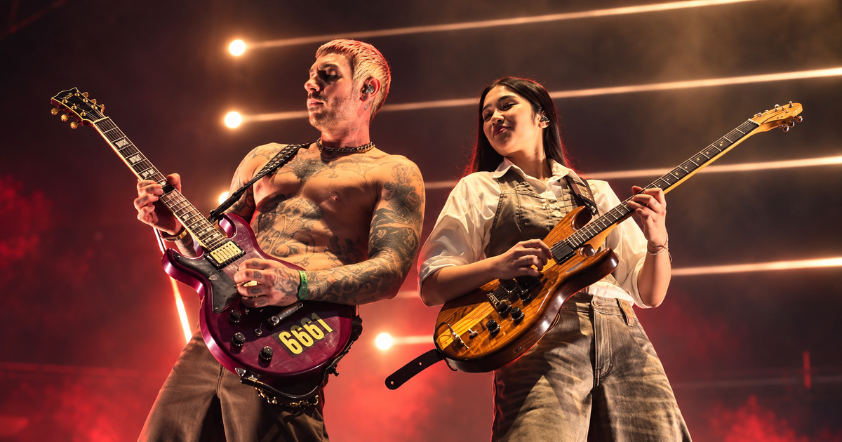 Edited concert photograph of NeNe Royal playing guitar beside an Avenged Sevenfold guitarist in Singapore