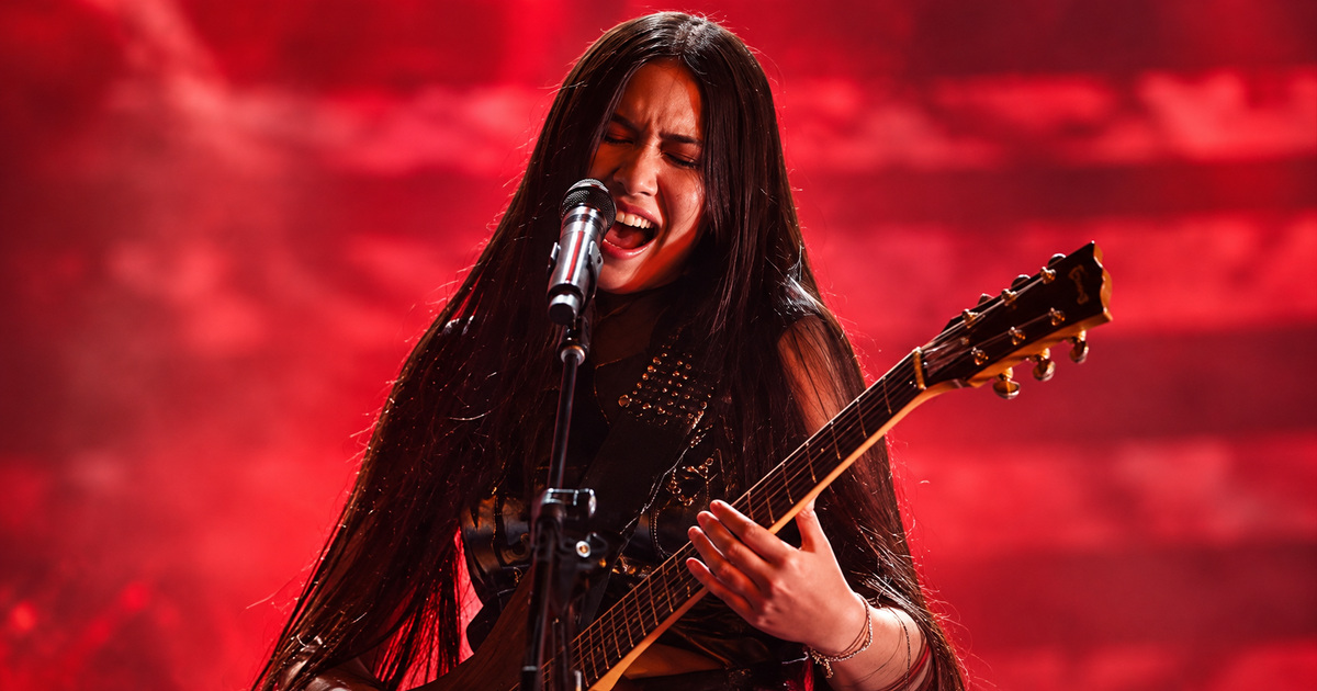 Edited concert image of NeNe Royal singing and playing guitar under red lighting